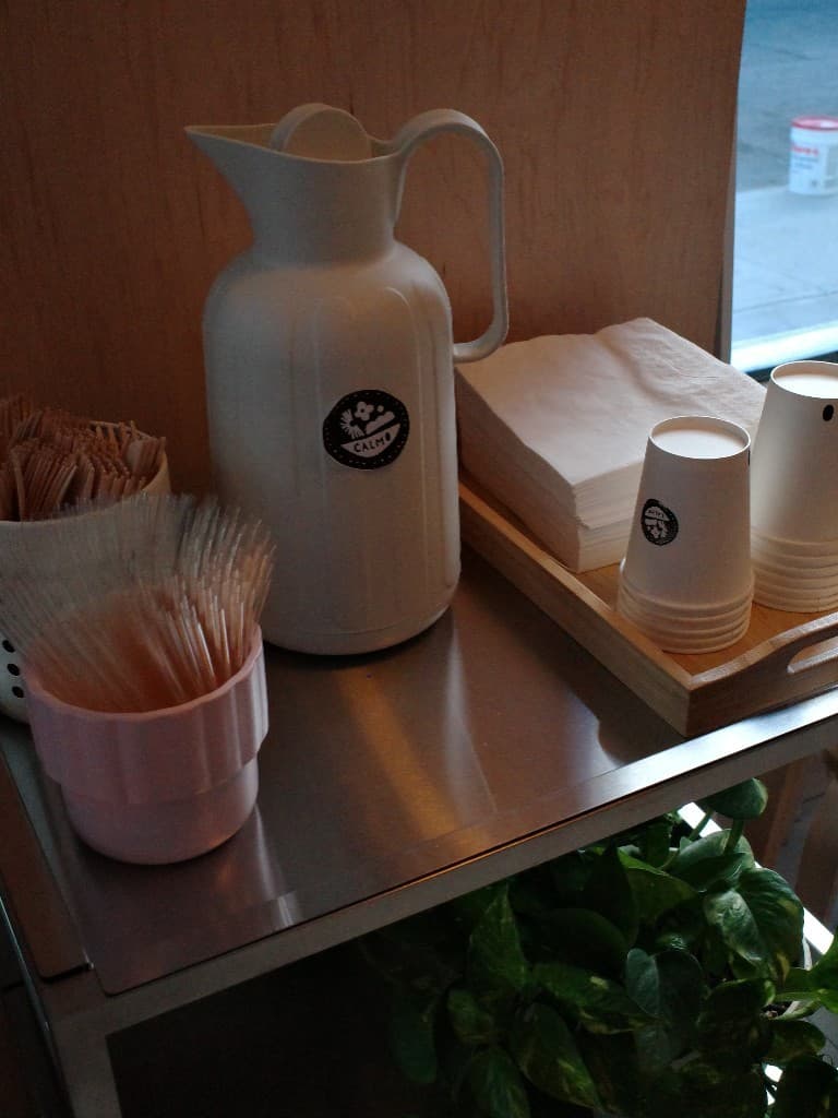 Self-service water, cups, and napkins at the Calmo counter